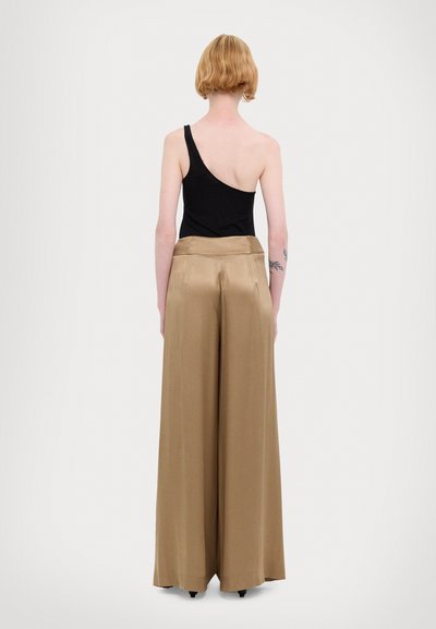 Zwarte ribbelige top met één schouder, gecombineerd met lichtbruine wijde satijnen broek, gezien van achteren, met een gladde textuur en strakke lijnen.
