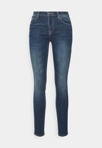 Jeans ajustados de color azul oscuro con ligero desgaste, cierre de botón en la parte frontal, cremallera y estilo de cinco bolsillos sobre un fondo blanco.