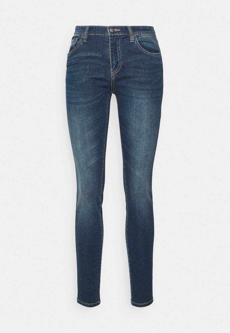 Jeans ajustados de color azul oscuro con ligero desgaste, cierre de botón en la parte frontal, cremallera y estilo de cinco bolsillos sobre un fondo blanco.