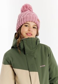 Grüne und beige Winterjacke mit hohem Kragen, mit einem rosa Logo. Rosa Strickmütze mit einem Pompon oben. Weicher Stoff, lässiger Stil.