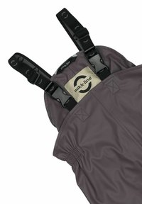 Tmavohnedé nepremokavé overal s nastaviteľnými čiernymi pásmi a prackami. Obsahuje nášivku s logom a elastické manžety pre pohodlné nosenie.