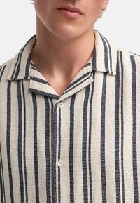 Gestreepte korte mouwen blouse in beige en marineblauw, met een textuurstof, knoopsluiting, klassieke kraag, met verticale lijnen en een geweven patroon.