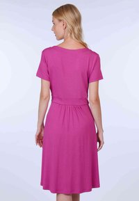 Enganliegendes rosa Kleid aus glattem Stoff, mit kurzen Ärmeln, einer taillierten Taille und einem weit ausgestellten Rock. Das Design hat einen Rundhalsausschnitt.