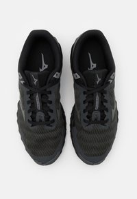 Le scarpe da ginnastica nere e grigio scuro presentano una tomaia in mesh, un tessuto testurizzato, chiusura con lacci e una suola in gomma con un motivo a zigzag.