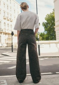 Lichtgrijze oversized t-shirt gecombineerd met hoge taille, wijde broek met een bruine luipaardprint. Zachte textuur, comfortabele pasvorm.
