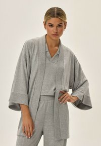 Szary zestaw odzieży domowej z dzianiny, składający si ę z kurtki w stylu kimono z szerokimi rękawami, dopasowanego topu oraz spodni na gumce. Miękka tekstura.