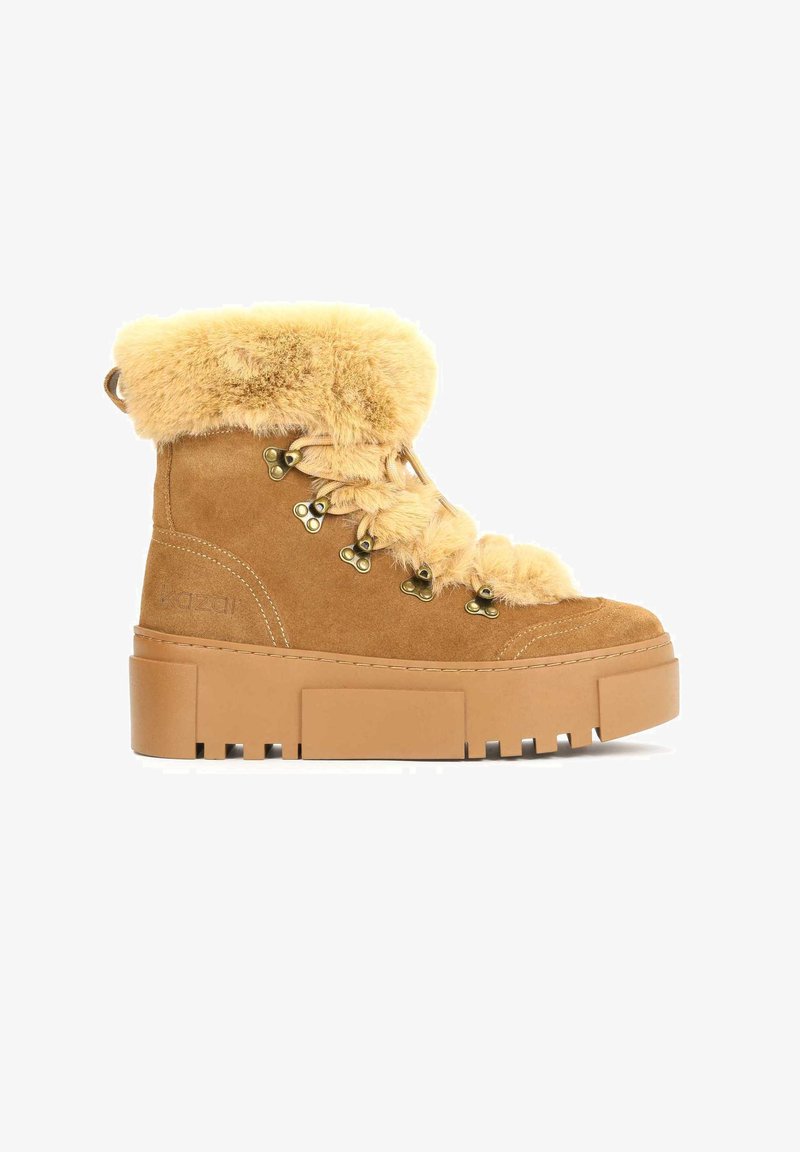 Tan suede ankle boot with faux fur trim at the cuff, metal eyelets, and a chunky platform sole featuring a rugged tread pattern.