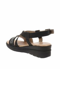 Sandal nera con tacco a zeppa, caratterizzata da un design a fascia e brillanti decorativi sulla punta. Fodera interna liscia e suola testurizzata.