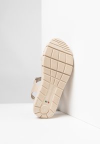 Sandalo beige con suola in gomma testurizzata, dotato di una presa decorata e cinturini regolabili per una vestibilità sicura. Logo del marchio visibile sulla suola.