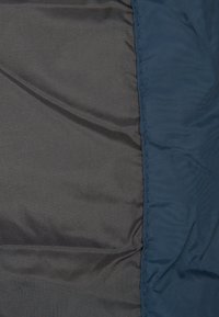 Marineblåt og sort stof med en glat tekstur, med en synlig søm langs kanten. Letvægtsmateriale velegnet til overtøj.