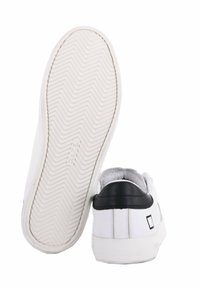 Sneakers bianche con tomaia in pelle liscia, dettagli neri sul tallone e suola in gomma con un motivo a spina di pesce.