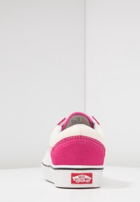 Vans lenkkarit, joissa on vaaleanpunainen mokkanahkaaccentti kantapäässä, kerma väri kanvaasipäällinen, musta pohja ja valkoinen brändityö yksityiskohtana kantapäällä.