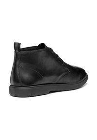 Botín de cuero negro con textura suave, puntera redondeada, diseño de cordones y suela baja de goma. Presenta una lengüeta en la parte posterior.