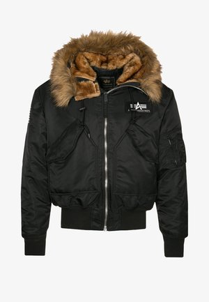 Chaqueta bomber negra con capucha de piel sintética marrón desmontable, cierre de cremallera, puños elásticos y múltiples bolsillos frontales. Presenta un detalle de logo en relieve.