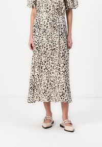 Leopardmønstrete midi-kjole med plisserte detaljer, knyttet midje og korte puffy-ermer. Kombinert med beige sko med reim og spenne.