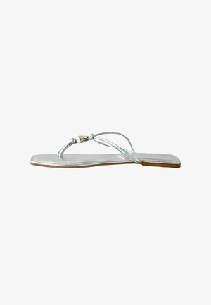 Sølvfarvet flad sandal med tynde stropper og en metallisk spænde, med firkantet tå og lys brun sål.