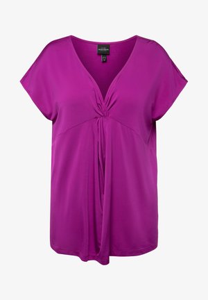 Lila lyhythihainen paita V-päähineellä ja kierretty solmu yksityiskohtana etuosassa.
