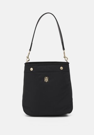 Black shoulder bag with gold-tone logo, snap buttons, and detachable strap on a plain light background.