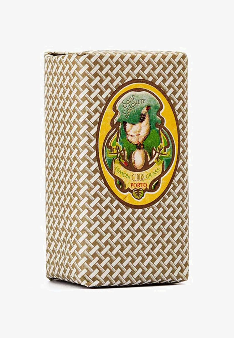 Seifenstück mit einem gewebten Muster in Braun- und Cremetönen. Mit einem runden Etikett, das eine Hühnerillustration und den Text "Lemon Claus Grass" zeigt.