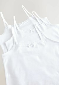 Witte katoenen hemdjes met dunne verstelbare bandjes, kantafwerking langs de halslijn en kleine strikjes. Gelaagde positionering toont diepte.