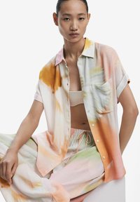 Ľahká, krátkopytá košeľa v pastelových farbách s pomalovaným vzorom; má vrecko a gombíky po celej dĺžke.