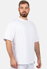 T-shirt bianca a maniche corte con scollatura rotonda, caratterizzata da un discreto logo vicino al colletto e una vestibilità rilassata per il comfort.