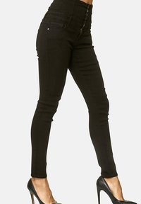 Vaqueros skinny negros de cintura alta, fabricados en denim, con un diseño ajustado, costuras sutiles y un cierre de cremallera frontal con botón.