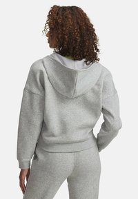 Šedá mikina s kapucňou, vyrobená z mäkkej látky. Má rebrované manžety a pás, uvoľnený strih a minimalistický dizajn.