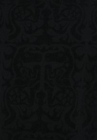 Μαύρο ύφασμα με περίπλοκο, ανάγλυφο αφηρημένο μοτίβο που παρουσιάζει συμμετρικά σχήματα και σπείρες σε υφή που θυμίζει βελούδο.