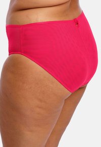 Bas de bikini taille haute de couleur rose vif, avec une texture lisse et un petit bouton décoratif au niveau de la taille.