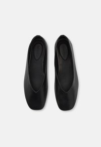 Ballerine in pelle nera con punta arrotondata e texture liscia. Presentano un taglio basso e un design minimalista. All'interno sono marchiate con "Calvin Klein."