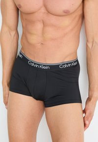 Zwarte Calvin Klein boxershorts met een zachte elastische tailleband met logo. Het materiaal lijkt rekbaar en aansluitend, wat de contouren benadrukt.