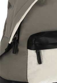 Rucsac gri cu exterior din material textil moale, bază din piele neagră și buzunar frontal alb căptușit, prevăzut cu fermoar.