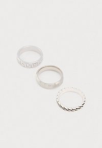 Kolm hõbesõrmust: üks geomeetrilise mustriga, üks siledat pinda omav ja üks lainelise servaga. Erinevad laius ja viimistlused.