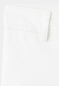 Gros plan sur la ceinture et la boucle de ceinture d'un jean ou pantalon en jean blanc uni.