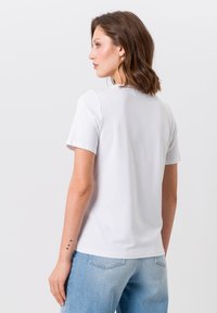 White short-sleeve t-shirt made of soft cotton, featuring a round neckline and smooth texture, paired with light blue denim jeans.