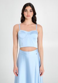 Cropped top azzurro chiaro con sottili spalline, presenta un collo a cuore e un busto strutturato, abbinato a una gonna fluida coordinata. Texture liscia.