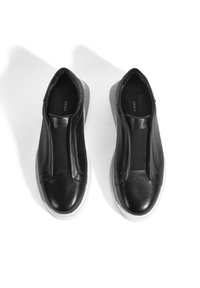 Schwarze Leder-Slipper mit elastischen Seitenpaneelen und einer weißen Gummisohle. Glatte Oberfläche mit runder Zehenform und minimalistischem Design.