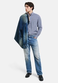 Chaqueta de mezclilla azul, camisa a cuadros en azul y blanco, jeans de color azul claro, zapatos negros. Un conjunto informal con texturas y colores variados.