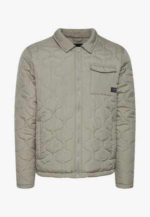 Lysgrå quiltet jakke med lynlås foran, spidse krave og en brystlomme. Materialet fremstår glat med en blød tekstur.