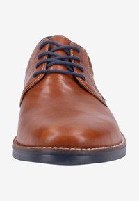 Scarpa in pelle marrone con finitura liscia, punta tonda e lacci blu navy. Una leggera cucitura mette in risalto i bordi e una suola scura in contrasto.