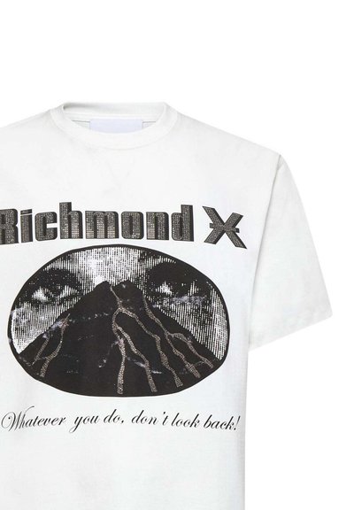 T-shirt in cotone bianco con una grafica nera di una montagna con occhi sopra, adornata con dettagli argento e il testo sottostante.
