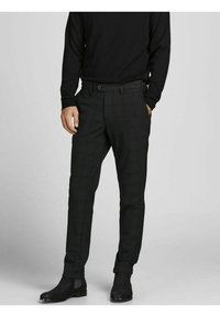 Black checkered trousers with a tailored fit, featuring a smooth texture, side pockets, and cuffed hems, paired with black boots.