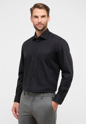 Schwarz langärmliges Hemd mit Button-Down-Kragen, einer einzelnen Brusttasche und einheitlicher Textur, getragen mit grauen Hosen.