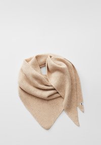 Écharpe en tricot beige pliée avec une extrémité pointue et une petite étiquette blanche sur fond clair.