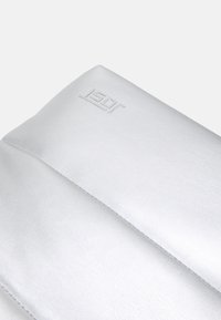 Stříbrná kožená kabelka s hladkou texturou a embosovaným logem. Má čisté linie a strukturovaný design, který zdůrazňuje minimalistickou eleganci.