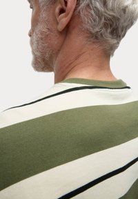 Zelené a krémové pruhované tričko s vroubkovaným kulatým výstřihem, vyrobené z měkkého materiálu, s černými akcenty v pruzích.