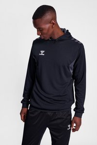 Felpa sportiva nera realizzata in tessuto testurizzato, con cappuccio regolabile e accenti grigi sui lati, abbinata a pantaloni neri coordinati.
