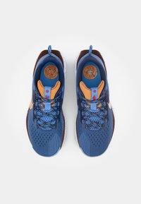 Blauwe sportieve sneakers met een bovenwerk van mesh, oranje accenten en een wit gespikkelde zool. Voorzien van veters en een rond logo op de tong.