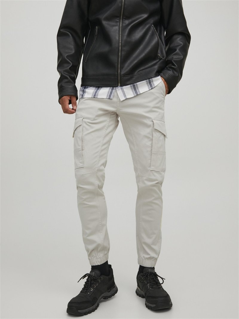 Pantalon cargo blanc avec des poignets élastiques, fabriqué en tissu mélangé de coton. Stylé avec des poches latérales et associé à une veste en cuir noire.